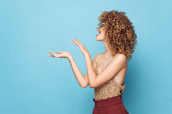 Attraktive Frau lockiges Haar Gesten Hände Seitenansicht blauer Hintergrund — Stockfoto