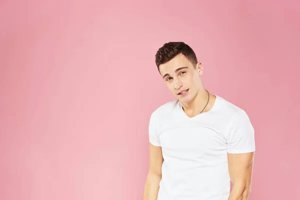 Alegre bonito homem em branco t-shirt emoções rosa isolado fundo — Fotografia de Stock
