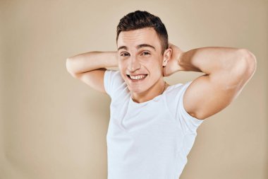 Sevimli duygusal adam beyaz tişört jesti elleri kırpılmış bej renkli stüdyo arka planı