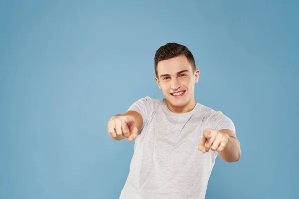 Vrolijk man in een wit t-shirt gebaren met zijn handen emoties blauw achtergrond — Stockfoto