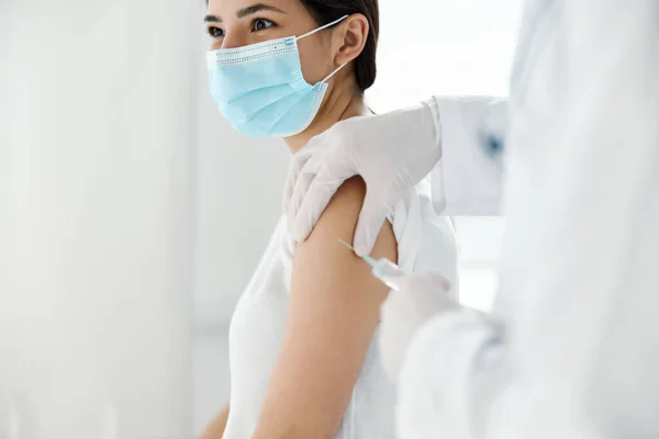 Medico in guanti protettivi inietta un vaccino nella spalla di una paziente vaccinata con covid — Foto Stock