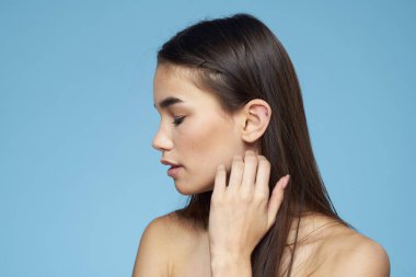 Güzel bir kadın. Çıplak omuzlar. Saç bakımı, yakın plan mavi arka plan.