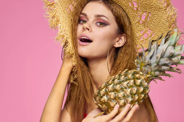 Mulher com uma arma nas mãos de um chapéu de palha maquiagem brilhante frutas exóticas verão fundo rosa — Fotografia de Stock