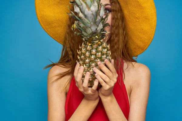 Kvinna i gul hatt med ananas i händerna känslor rolig livsstil sommar frukt blå bakgrund — Stockfoto