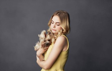 Sarı elbiseli, küçük safkan köpek dostluğu olan sevimli bir kadın.