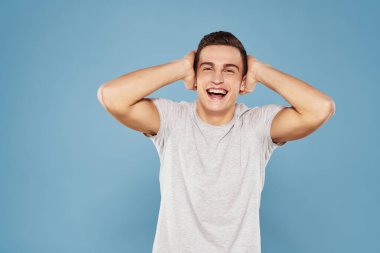 Beyaz tişörtlü neşeli bir adam elleri ve duyguları mavi arka planda hareket ediyor.