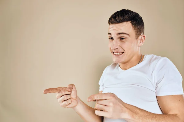 Emocional hombre blanco gestos camiseta con manos estilo de vida fondo beige — Foto de Stock