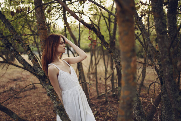 Pretty woman leaning on tree trunk outdoors in garden cropped view. High quality photo