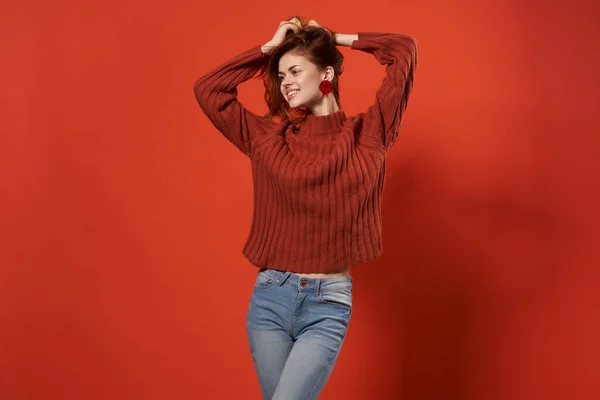 Mulher emocional em suéter vermelho segurando cabelo estúdio decoração fundo vermelho — Fotografia de Stock