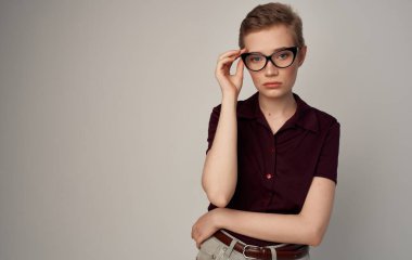 Güzel, kısa saçlı, gözlüklü, zarif, şık gömlekli bir kadın.