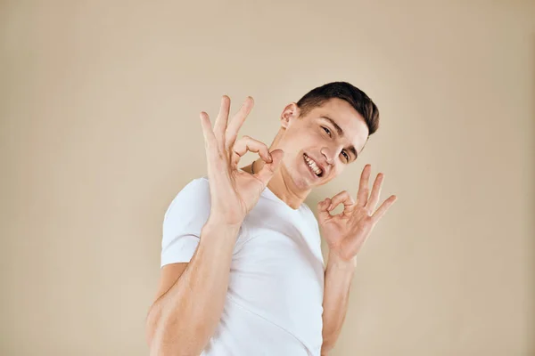 Känslomässig man vit t-shirt gester med händer livsstil beige bakgrund — Stockfoto