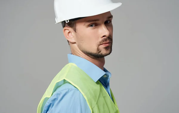 노란 조끼를 입고 회색 배경에 흰 헬멧을 쓴 남자 근로자 — 스톡 사진