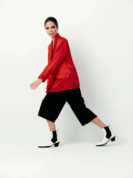 Kobieta w czerwonej kurtce i w czarnych spodniach biały buty styl mody — Zdjęcie stockowe