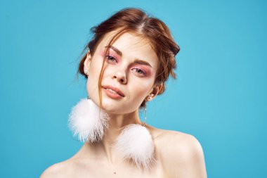 Çekici bir kadın parlak makyaj küpeleri takı omuzları mavi arka plan