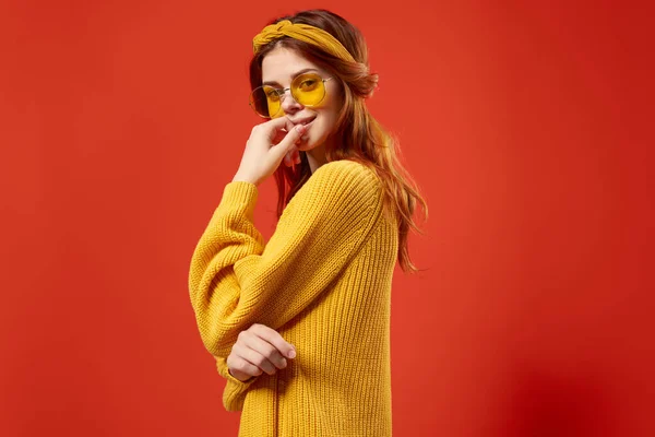 Jolie femme portant des lunettes jaune chandail émotions casual porter fond rouge — Photo