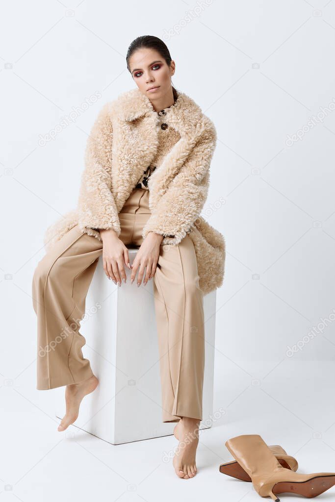 brunette with bright makeup on her face beige coat fashionable clothes