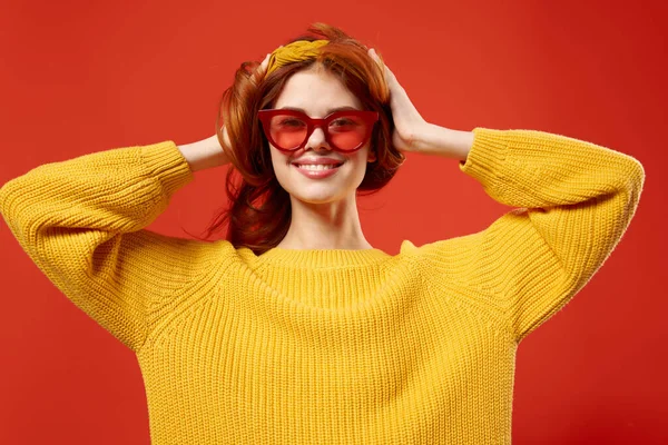 Vacker kvinna i gul tröja röda glasögon fashionabla kläder närbild röd bakgrund — Stockfoto