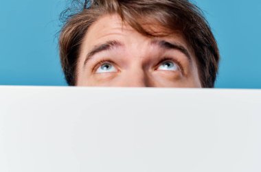 Adam bariyer reklamının arkasından dışarı bakıyor. Boşluk mavi arkaplan kırpılmış görünümü kopyala