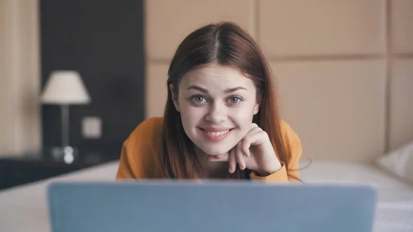 Mujer bastante alegre se encuentra en la cama delante de Internet portátil — Foto de Stock