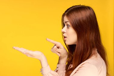 Güzel bir kadın sarı arka plan cazibesiyle el kol geziyor.