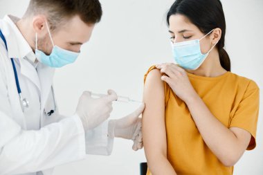 Tıbbi maskeli doktor bir kadına omuz aşısı yapıyor. Sağlık aşısı.