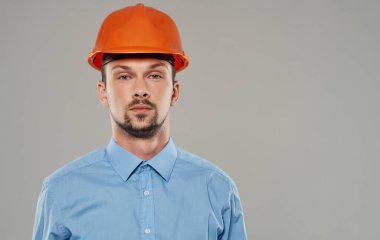 Turuncu boyalı bir erkek mimar ve gri bir arka plan portresi üzerinde mavi gömlekli.