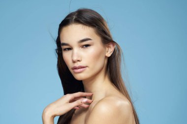 Çıplak omuzlu, uzun saçlı, kozmetik ürünleri olan bir kadın.