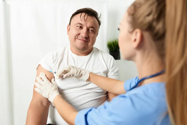 Kvinna läkare injektioner i axeln av en man patient hälsovård covid vaccination — Stockfoto
