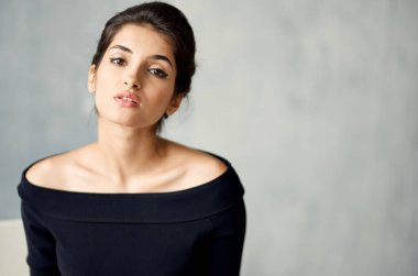 Gri arka plan portresi üzerinde gece elbisesi ve küpeleri olan romantik bir bayan.