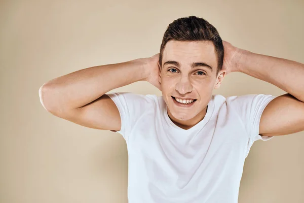 Lindo hombre emocional blanco gesto camiseta con las manos recortadas vista beige fondo del estudio —  Fotos de Stock