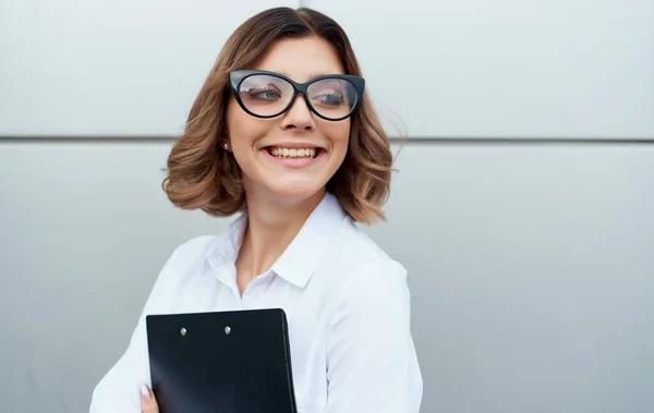 Щаслива бізнес-леді біля будівлі з документами в руках і окулярах на обличчі обрізаний вид — стокове фото