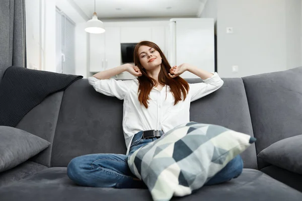 家の中で快適なソファに枕を持つ女性 — ストック写真