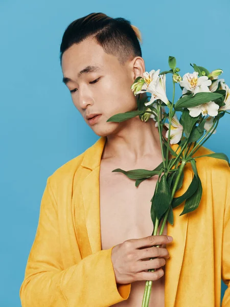 Um cara de aparência asiática com um buquê de flores retrato casaco amarelo sintético winterizer aparência asiática — Fotografia de Stock