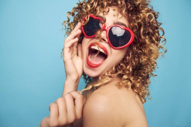 Neşeli kadın çıplak omuzlar, duygular kırmızı dudaklar mavi arka plan güneş gözlükleri. 