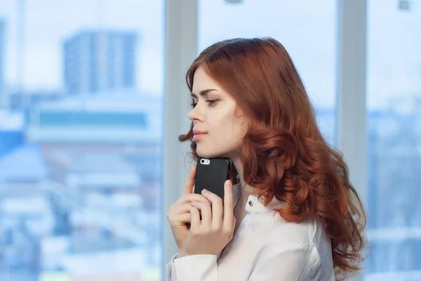Mujer pelirroja con teléfono en las manos en la tecnología de oficina profesional — Foto de Stock