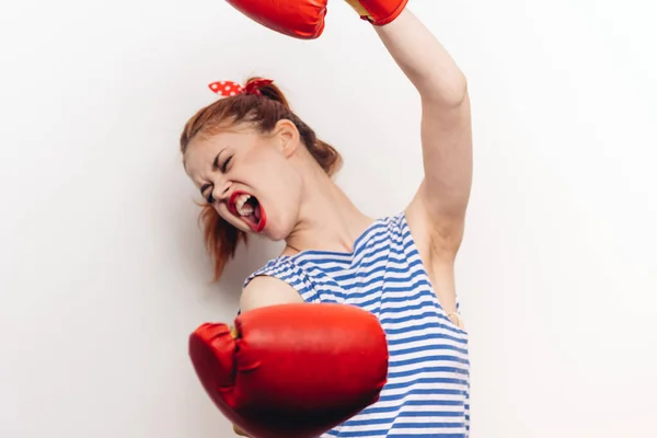 Sportive agressive en gants de boxe et un t-shirt rayé se bat sur un fond clair — Photo