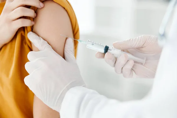 Läkare i en medicinsk klänning som ger en spruta i axeln på en kvinna i en gul t-shirt i en sjukhusvaccination — Stockfoto