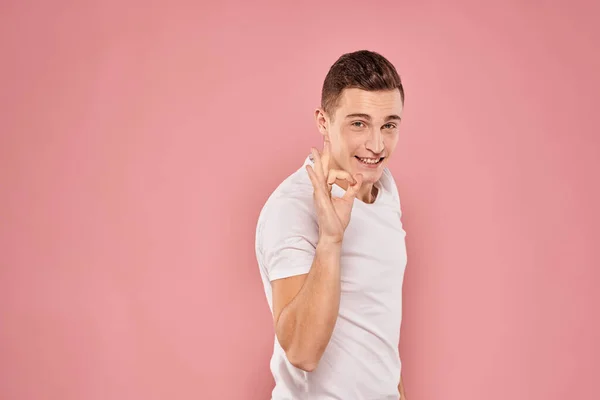 Homme émotionnel gestuelle avec ses mains blanc t-shirt rose fond isolé — Photo