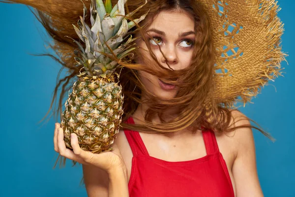 Mulher em um chapéu de palha com abacaxi em suas mãos cabelo ondulado frutas exóticas você verão azul fundo férias — Fotografia de Stock