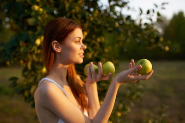 Happy woman with green apples in her hands in nature near a tree In the meadow — Stock Photo, Image