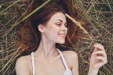 Mutlu kadın samanlıkta beyaz bir elbiseyle uzanır ve elleriyle el kol hareketi yapar.