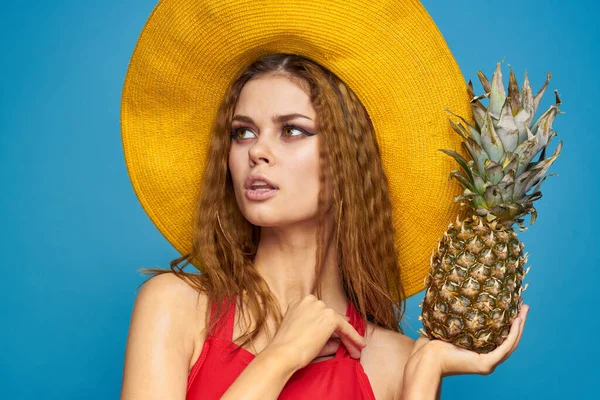 Mulher de chapéu amarelo com abacaxi nas mãos emoções divertido estilo de vida verão fruta azul fundo — Fotografia de Stock