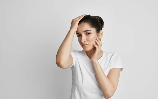 Een vrouw in een wit t-shirt houdt haar gezicht met hoofdpijn en nigatieve gezondheid — Stockfoto