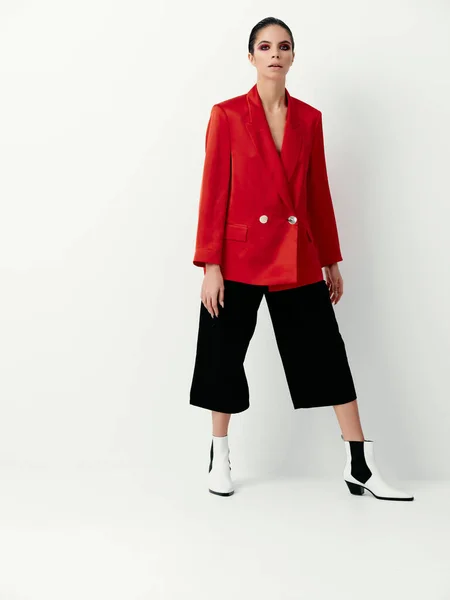 浅色背景下穿着红色夹克和时髦靴子的时髦黑发女人 — 图库照片