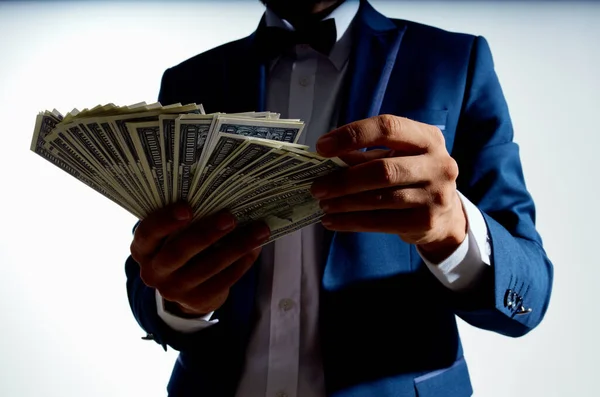 rich guy with a bundle of big money and in a classic suit on a light background