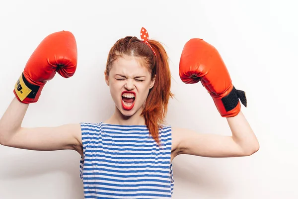 Woman boxer in a t-shirt and in red gloves hairstyle makeup light background — Stock Photo, Image