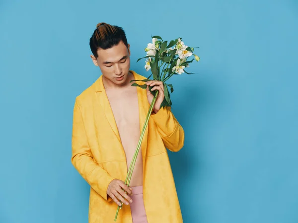 Uomo romantico in un cappotto giallo con un bouquet di fiori profumati sfondo blu — Foto Stock