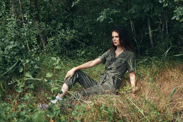 Γυναίκα με αθλητική φόρμα κάθεται στο γρασίδι στο δάσος — Φωτογραφία Αρχείου