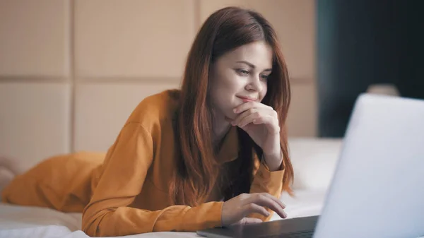 Emotionele vrouw in de slaapkamer ligt voor de laptop communicatie rust — Stockfoto