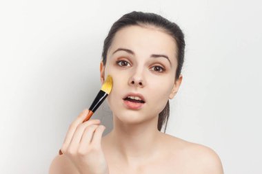 Saçı çekilmiş esmer, çıplak omuzlu makyaj temizleyicisi.